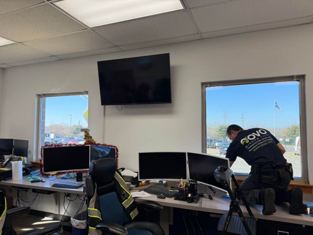 OOVO technician installs commercial bird film on office desk windows in DFW